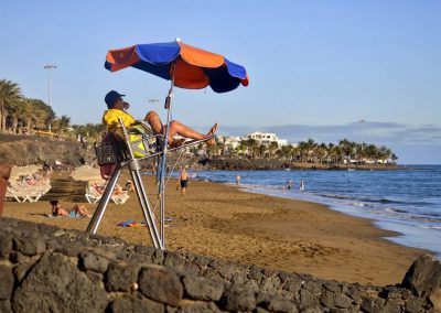 Lifeguard on beach sitting under umbrella
